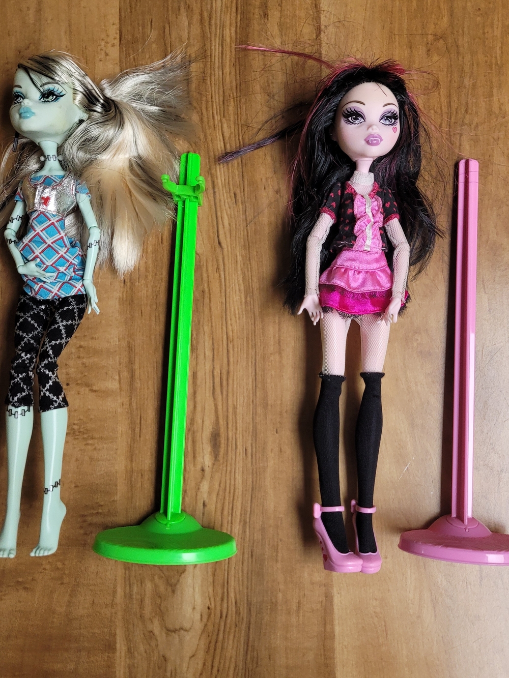 monster high black-haired doll in pink outfit with pink stand